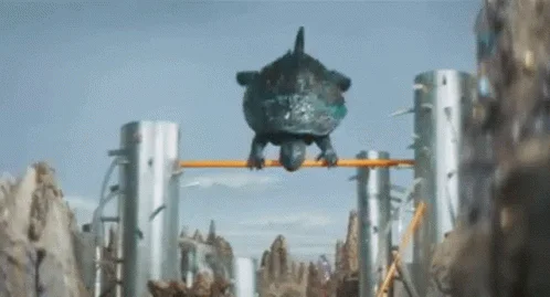 Gamera kaiju doing flips on horizontal bar.