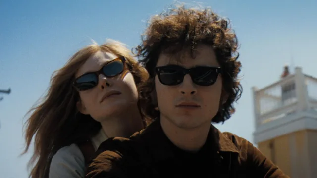 promotional still from a complete unknown featuring timothée chalamet as bob dylan on a motorcycle with his girlfriend played by elle fanning