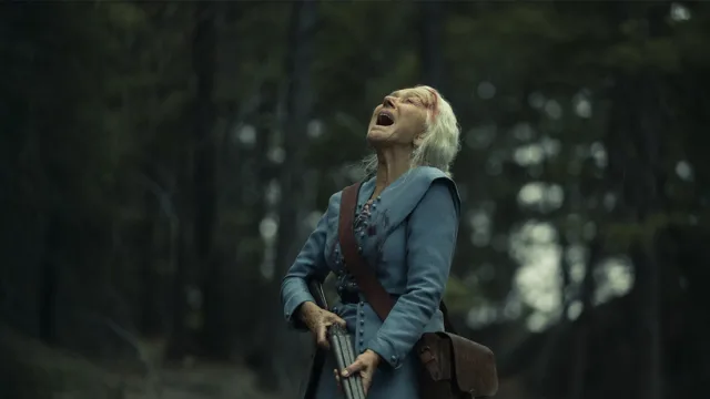 helen mirren holding a shot gun and yelling to the heavens while in the woods in a still from season 1 of 1923
