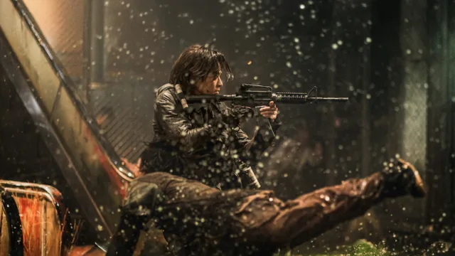 the main character in train to busan presents peninsula brandishing an automatic rifle as a zombie dives for him