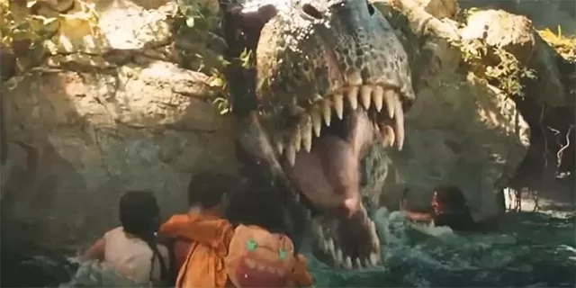 xciting scene from Jurassic World: Rebirth featuring a massive, roaring dinosaur emerging from a cave with sharp teeth, as people in the water look on in fear, captured in a thrilling moment from the movie, reviewed on https://worthitorwoke.com
