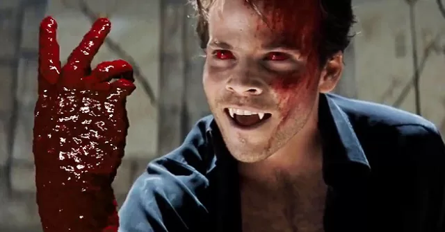 Stephen Dorff as Deacon Frost in Blade 1998 vampire scene: grinning with fangs and red eyes, raising blood-soaked hands in peace sign against stone wall—iconic example of dated, gooey CGI blood effects critiqued vs. modern VFX in The Witcher season 4.