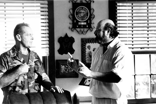 Rob Reiner directs Jack Nicholson as Colonel Nathan Jessup on the set of the 1992 courtroom drama A Few Good Men, in an intense behind-the-scenes moment featuring military decor including a United States Marine Corps emblem on the wall.