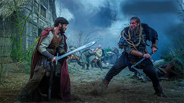 The Pendragon Cycle: Rise of the Merlin fight scene: Tom Sharp as Merlin sword clashing with barbarian axe invader in misty chaotic battle Roman-occupied Britain – DailyWire+ 2026 Arthurian legend origin series starring Rose Reid as Charis, James Arden as Taliesin – anti-woke review, WOKE-O-METER rating & conservative Christian family-friendly verdict exposing woke agenda on WorthItOrWoke.com